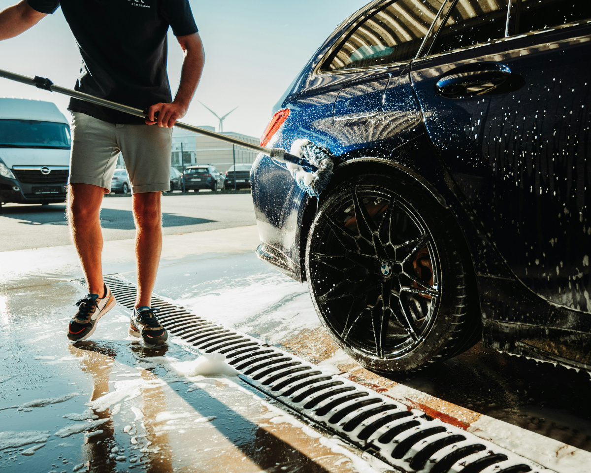 photo of a man washing a car practicing best car paint protection techniques